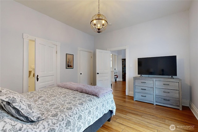 bedroom featuring a notable chandelier, light wood-type flooring, and baseboards