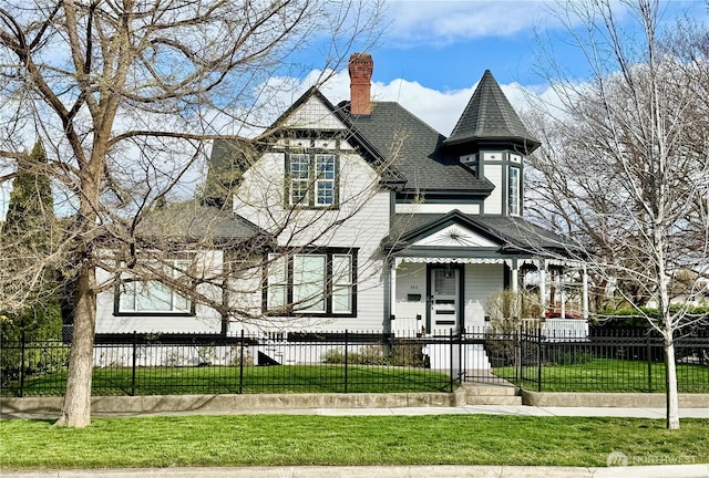victorian home featuring a fenced front yard, a chimney, a front yard, and roof with shingles