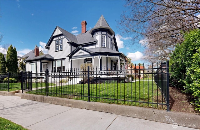 victorian-style house featuring a fenced front yard, a front lawn, and a chimney