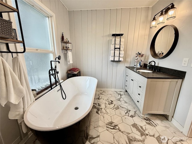 bathroom featuring a soaking tub, vanity, baseboards, and wooden walls