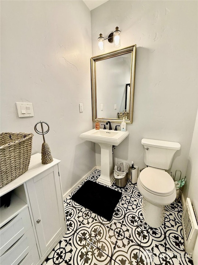 half bath featuring a wall mounted air conditioner, tile patterned floors, baseboards, and toilet