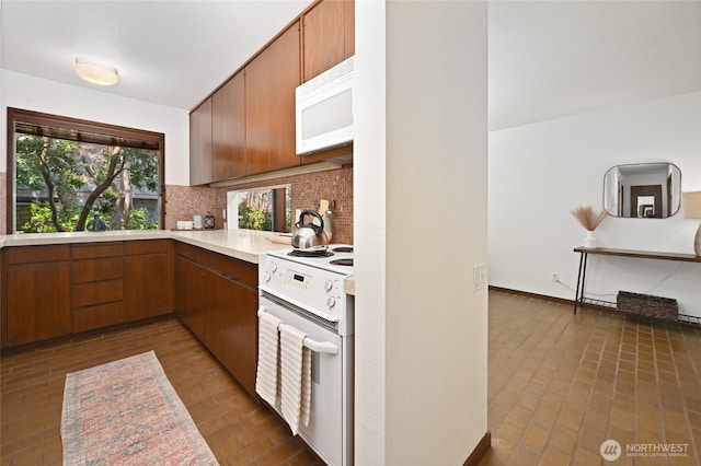 2312 W Crockett St, Seattle, WA 98199 - kitchen with light countertops, white appliances, brown cabinetry, brick floor, and decorative backsplash
