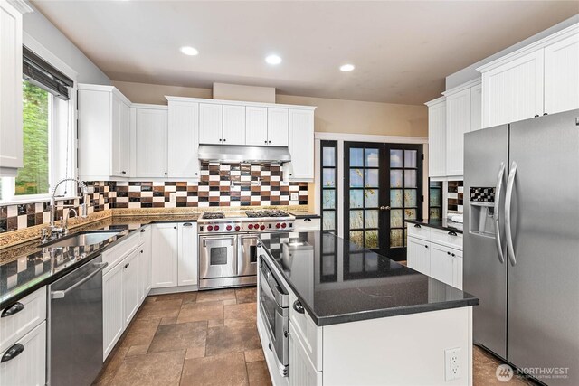 kitchen with appliances with stainless steel finishes, a sink, under cabinet range hood, decorative backsplash, and recessed lighting