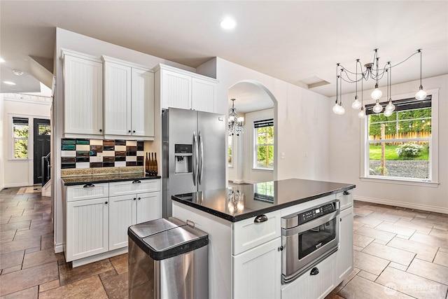 kitchen with stainless steel fridge with ice dispenser, a chandelier, dark countertops, arched walkways, and white cabinets