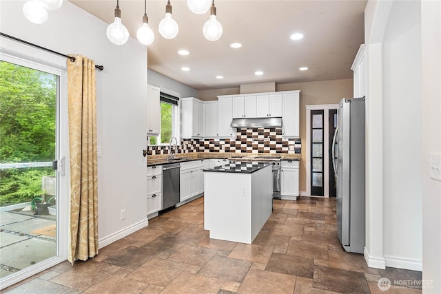 kitchen with appliances with stainless steel finishes, under cabinet range hood, tasteful backsplash, dark countertops, and white cabinets