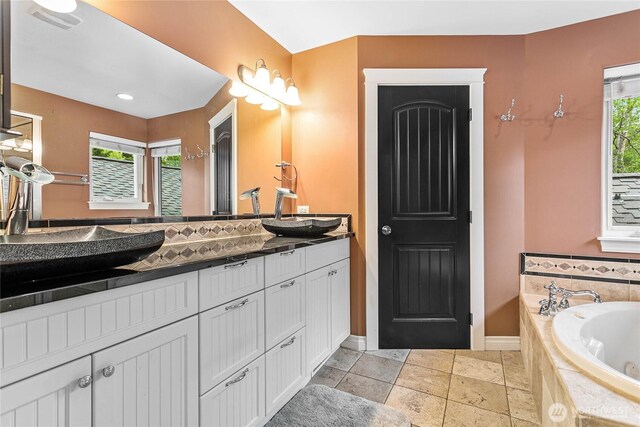 full bathroom featuring a garden tub, vanity, and baseboards