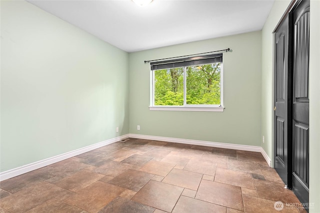 unfurnished bedroom with baseboards and stone tile flooring
