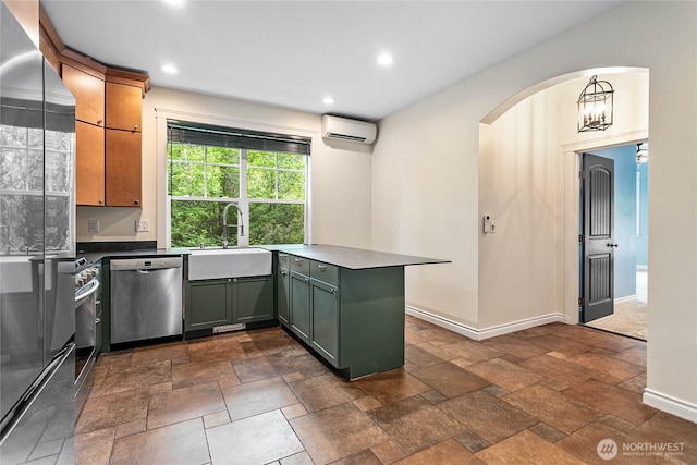 kitchen with appliances with stainless steel finishes, a sink, a wall mounted AC, a peninsula, and baseboards