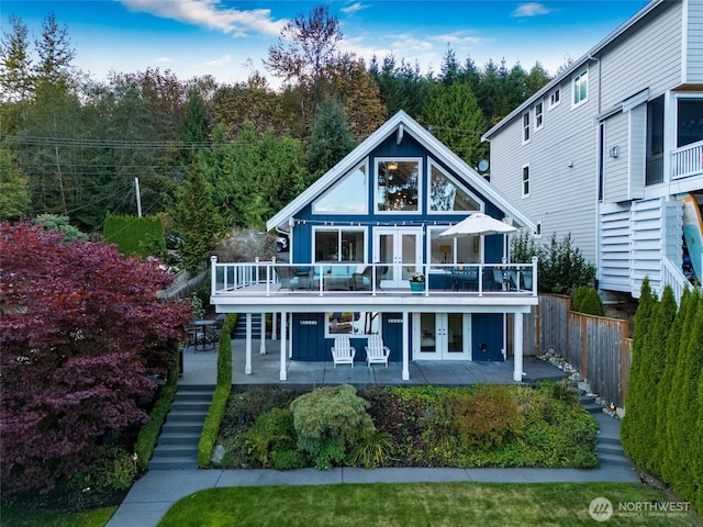 rear view of house featuring stairway, a patio area, a deck, board and batten siding, and french doors