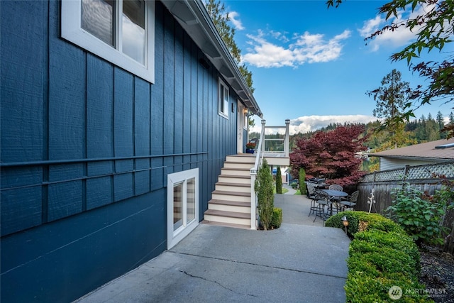 view of property exterior featuring fence, a patio area, and stairs