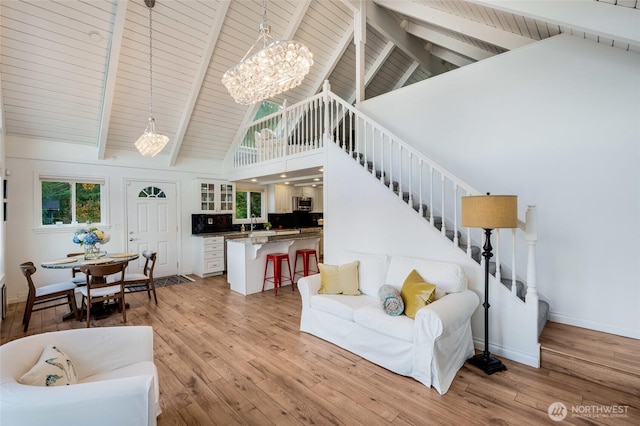 living room with baseboards, high vaulted ceiling, light wood-style floors, and stairway
