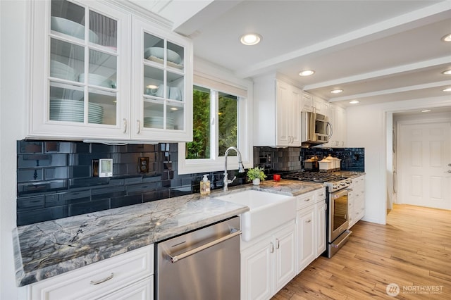 kitchen with light stone counters, beam ceiling, stainless steel appliances, and a sink