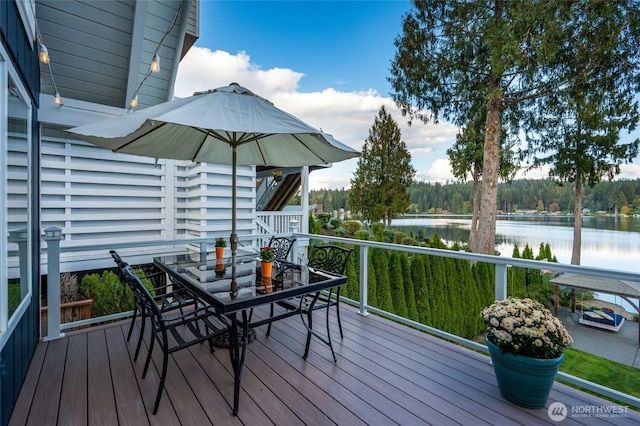 deck with outdoor dining area and a water view