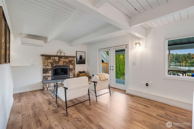 living area with a fireplace, beam ceiling, an AC wall unit, and hardwood / wood-style flooring