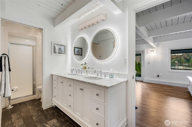 bathroom with beam ceiling, a stall shower, and a sink