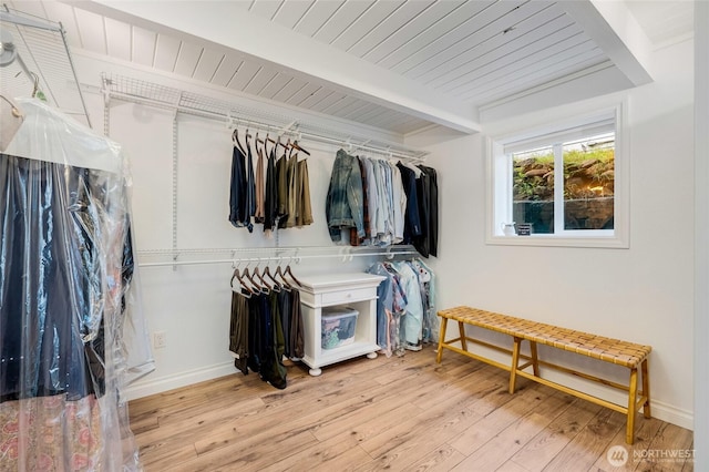 spacious closet featuring beamed ceiling and wood finished floors