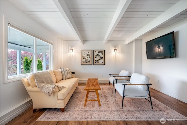 living area with beamed ceiling, wood finished floors, and baseboards
