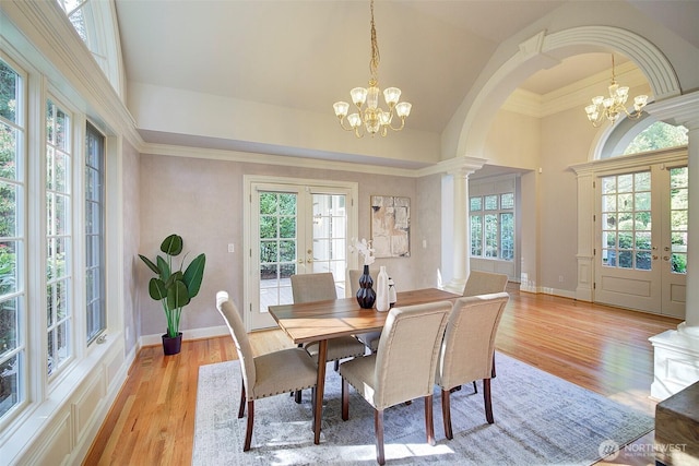 dining room with plenty of natural light, a notable chandelier, light wood finished floors, and french doors