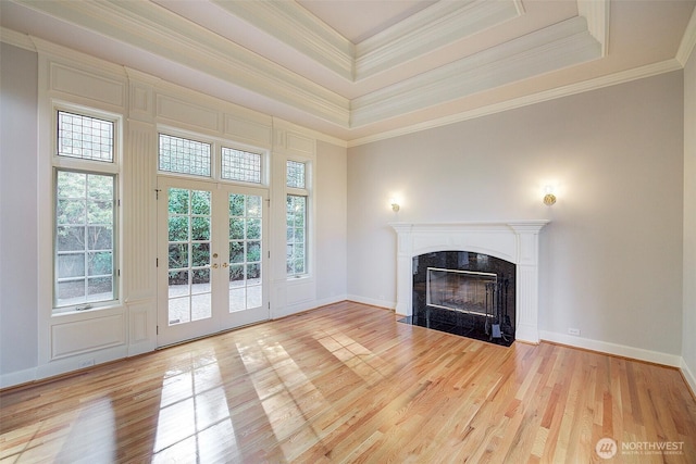 unfurnished living room with french doors, a raised ceiling, wood finished floors, and a fireplace
