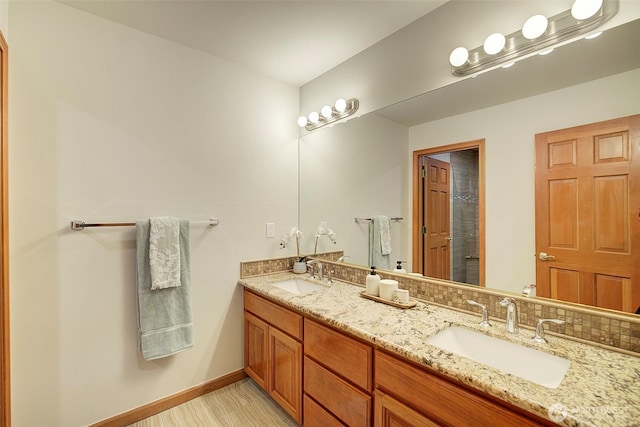bathroom featuring tasteful backsplash, double vanity, a sink, and baseboards