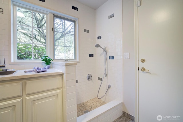 full bathroom featuring tiled shower and visible vents