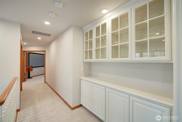 hallway with visible vents, baseboards, recessed lighting, and light colored carpet