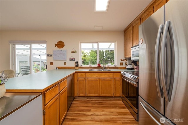 1903 Elhardt Dr, Camano Island, WA 98282 - kitchen with appliances with stainless steel finishes, a sink, light wood-style floors, a peninsula, and light countertops