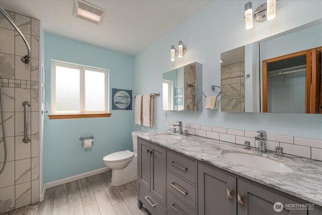 1903 Elhardt Dr, Camano Island, WA 98282 - bathroom featuring tiled shower, toilet, double vanity, baseboards, and wood finished floors