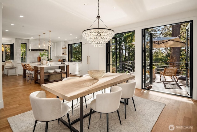 dining space featuring light wood finished floors, recessed lighting, and an inviting chandelier