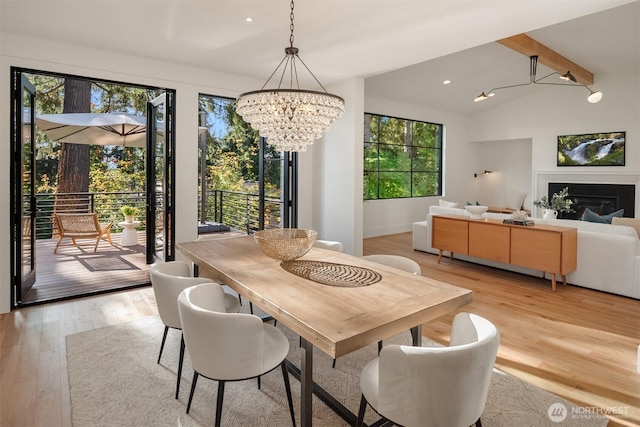 dining area featuring vaulted ceiling, recessed lighting, light wood finished floors, a notable chandelier, and a glass covered fireplace