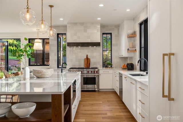 kitchen featuring a sink, open shelves, appliances with stainless steel finishes, light wood-type flooring, and wall chimney range hood