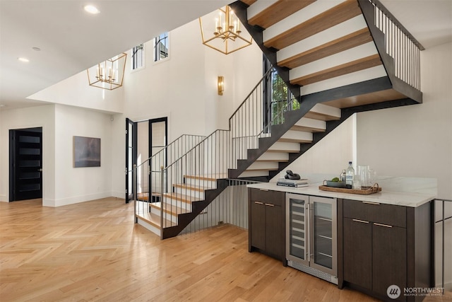 bar featuring indoor bar, stairs, a chandelier, and beverage cooler