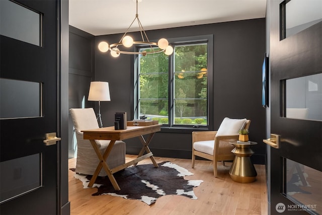 home office with a wealth of natural light, a notable chandelier, and light wood-type flooring