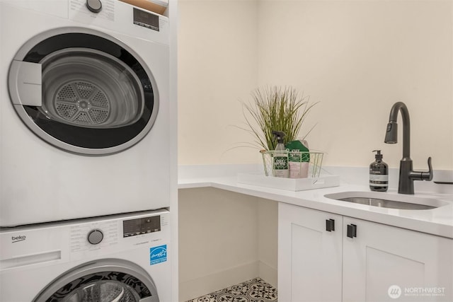 clothes washing area with a sink, cabinet space, and stacked washer / drying machine