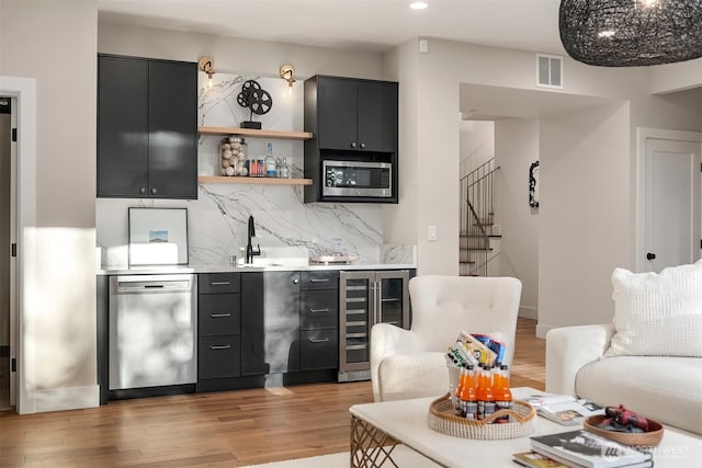 interior space featuring visible vents, stainless steel appliances, dark cabinets, and beverage cooler