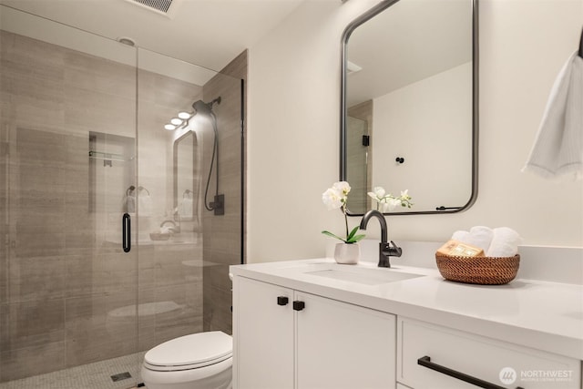 full bathroom featuring visible vents, toilet, a stall shower, and vanity