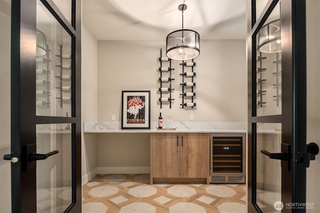 wine room featuring light tile patterned floors, baseboards, and wine cooler