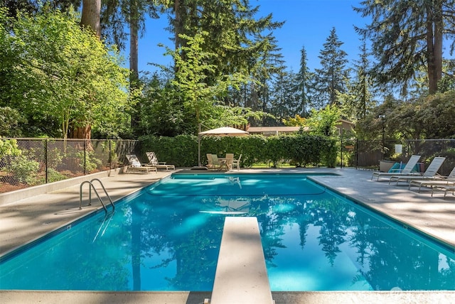 view of swimming pool with a diving board, a fenced in pool, fence, and a patio area