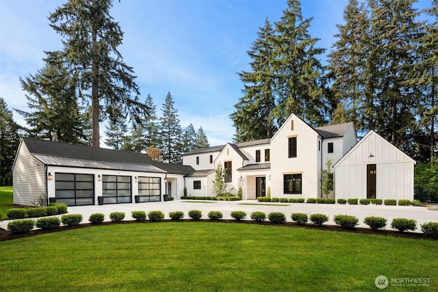modern farmhouse style home with a standing seam roof, metal roof, driveway, a front yard, and a garage