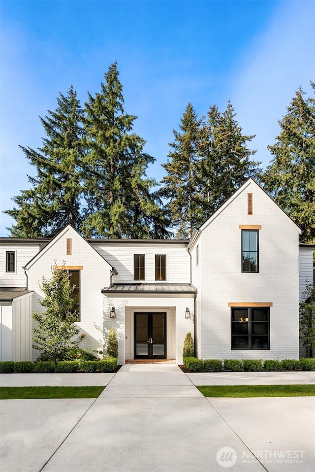 modern inspired farmhouse with metal roof, a standing seam roof, and french doors
