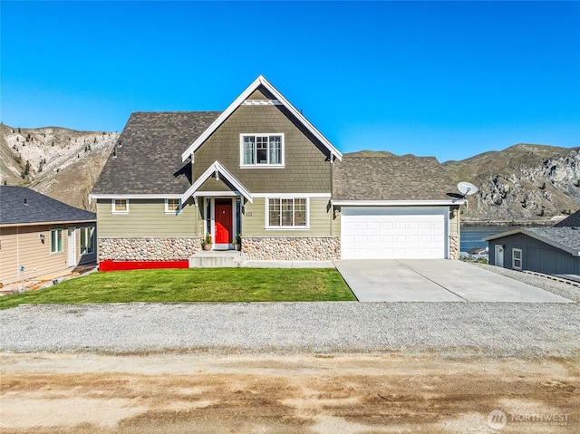 craftsman inspired home featuring a front yard, a mountain view, an attached garage, stone siding, and driveway