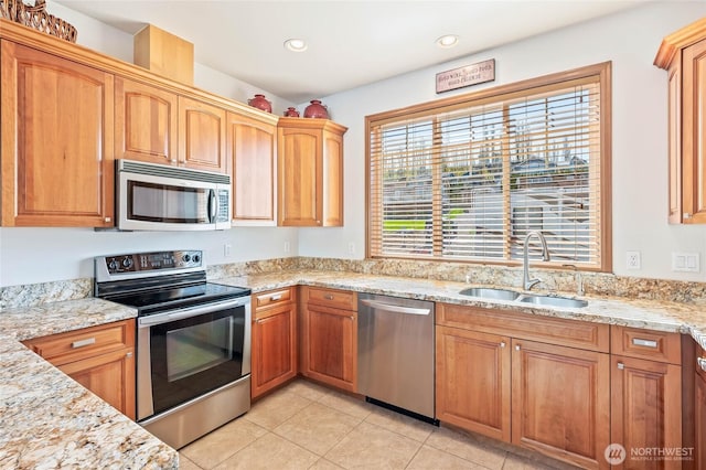 kitchen featuring light tile patterned floors, light stone countertops, stainless steel appliances, and a sink