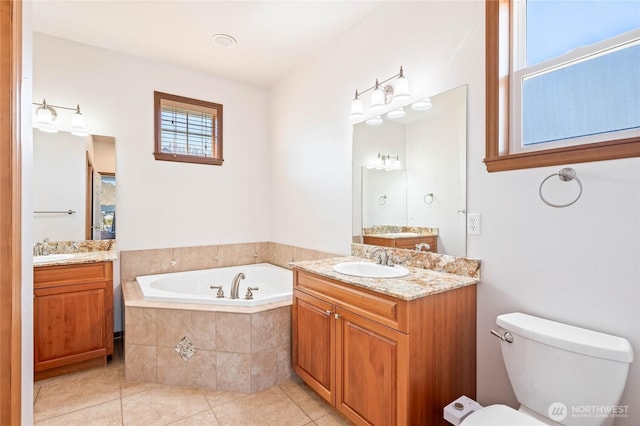 full bath featuring tile patterned floors, a garden tub, two vanities, and a sink