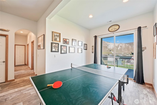 recreation room with recessed lighting, arched walkways, and light wood-style flooring