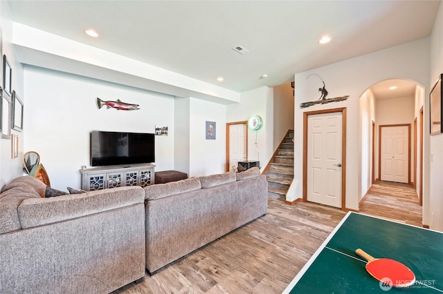living room featuring visible vents, arched walkways, light wood-type flooring, recessed lighting, and stairs