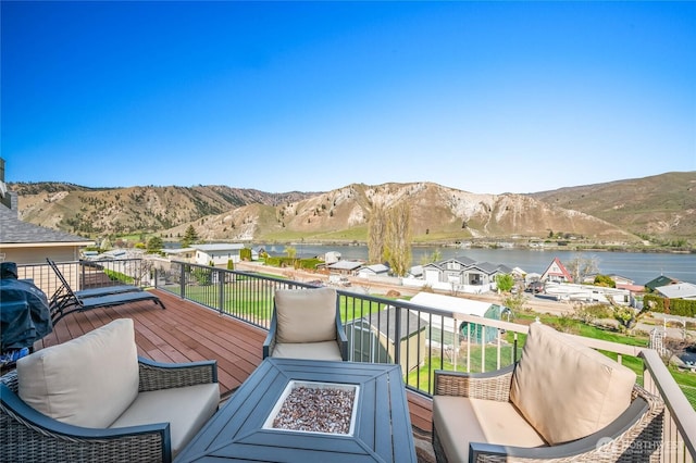 wooden terrace featuring an outdoor living space with a fire pit and a water and mountain view