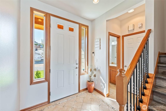 foyer featuring baseboards, a healthy amount of sunlight, stairs, and light tile patterned floors