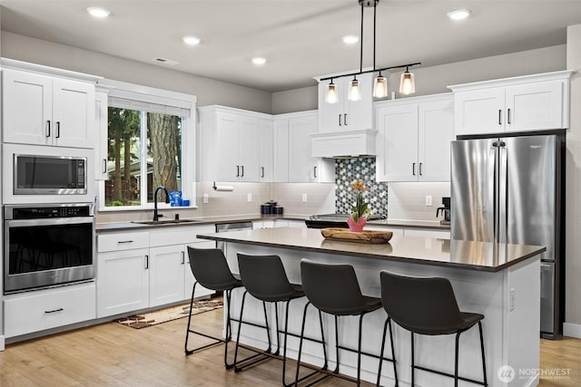 6620 165th Street Ct E, Puyallup, WA 98375 - kitchen featuring appliances with stainless steel finishes, a sink, a kitchen island, tasteful backsplash, and white cabinetry