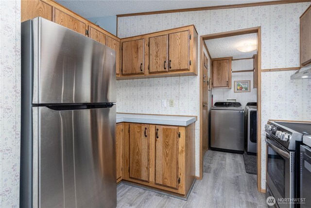 161 N Dow Mountain Rd, Hoodsport, WA 98548 - kitchen featuring washing machine and clothes dryer, wallpapered walls, brown cabinets, and appliances with stainless steel finishes