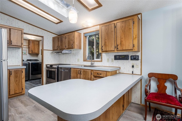 161 N Dow Mountain Rd, Hoodsport, WA 98548 - kitchen with washer and clothes dryer, a sink, appliances with stainless steel finishes, under cabinet range hood, and wallpapered walls